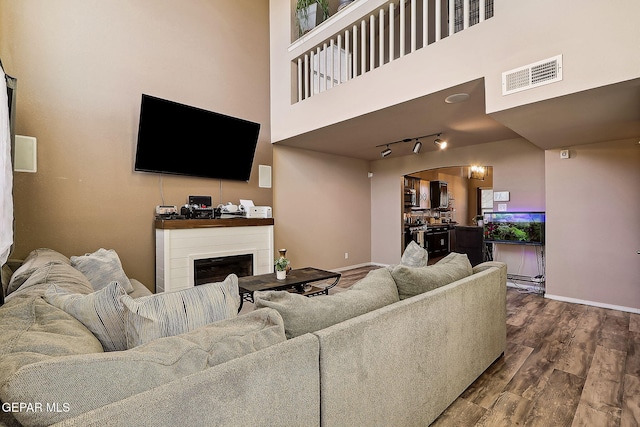 living area with a fireplace, wood finished floors, visible vents, and baseboards