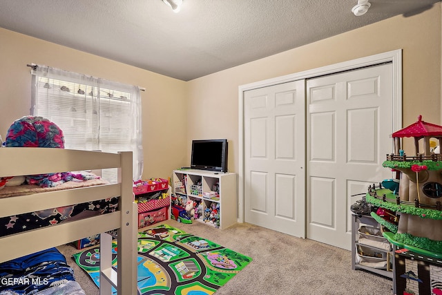 bedroom featuring light carpet, a textured ceiling, and a closet