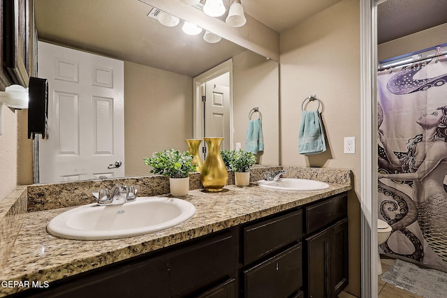 bathroom with toilet, a shower with curtain, double vanity, and a sink