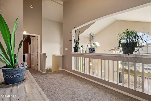 hall with high vaulted ceiling, baseboards, carpet flooring, and an upstairs landing