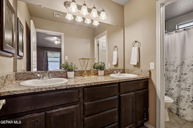 full bath with toilet, double vanity, visible vents, and a sink