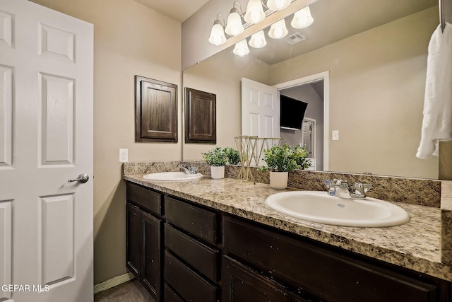 bathroom with double vanity, a sink, visible vents, and baseboards