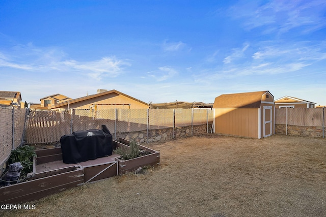 view of yard featuring a vegetable garden, a fenced backyard, an outdoor structure, and a shed