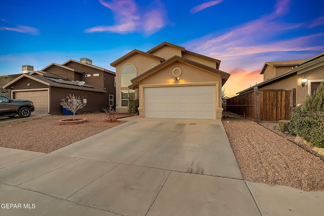 view of front of property with a garage, driveway, fence, and stucco siding