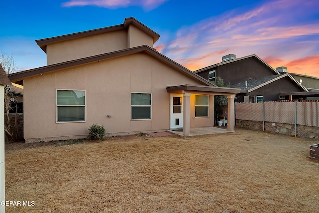 back of property with a patio, a lawn, fence, and stucco siding