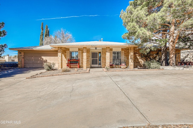 ranch-style home with a porch, brick siding, driveway, and an attached garage