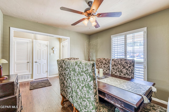 dining area with a ceiling fan, wood finished floors, visible vents, and baseboards