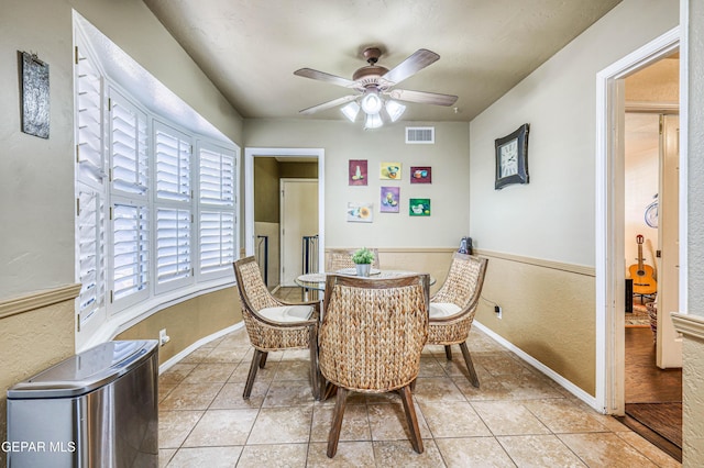 dining space with ceiling fan, wainscoting, light tile patterned flooring, and visible vents