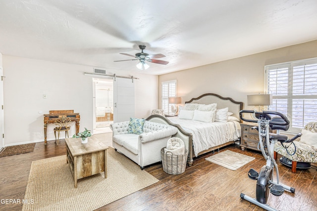 bedroom with a barn door, multiple windows, and wood finished floors