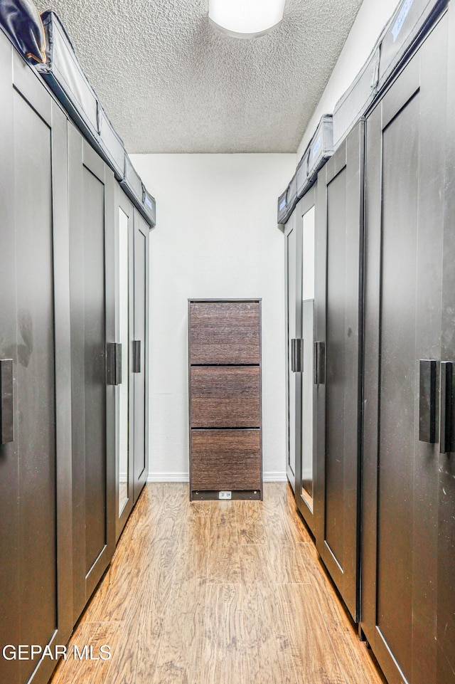 walk in closet with light wood-style floors