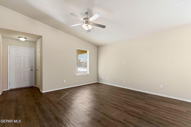 spare room featuring dark wood-style floors, vaulted ceiling, baseboards, and a ceiling fan