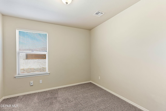 carpeted spare room featuring plenty of natural light, visible vents, and baseboards