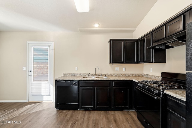 kitchen with light wood finished floors, baseboards, under cabinet range hood, black appliances, and a sink