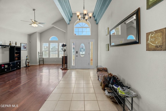 foyer entrance with light tile patterned floors, baseboards, beamed ceiling, high vaulted ceiling, and ceiling fan with notable chandelier