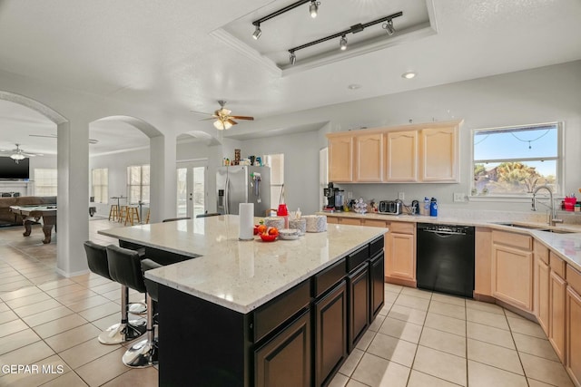 kitchen featuring a raised ceiling, dishwasher, light brown cabinets, stainless steel refrigerator with ice dispenser, and a sink