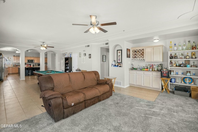 living area featuring arched walkways, a dry bar, light tile patterned floors, and visible vents