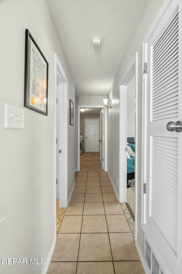 corridor featuring light tile patterned floors, baseboards, and visible vents