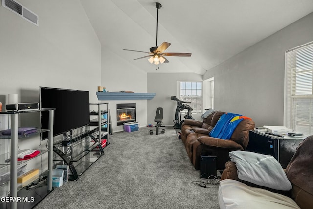 living room featuring ceiling fan, carpet floors, visible vents, vaulted ceiling, and a glass covered fireplace