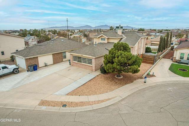 view of front of property with a residential view, brick siding, a mountain view, and driveway