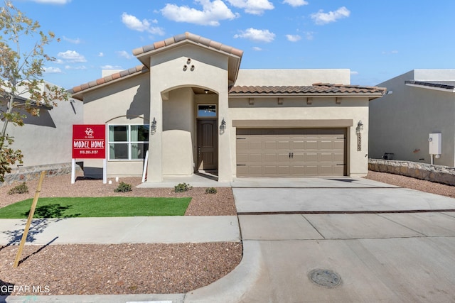 mediterranean / spanish-style home with a garage, a tile roof, concrete driveway, and stucco siding