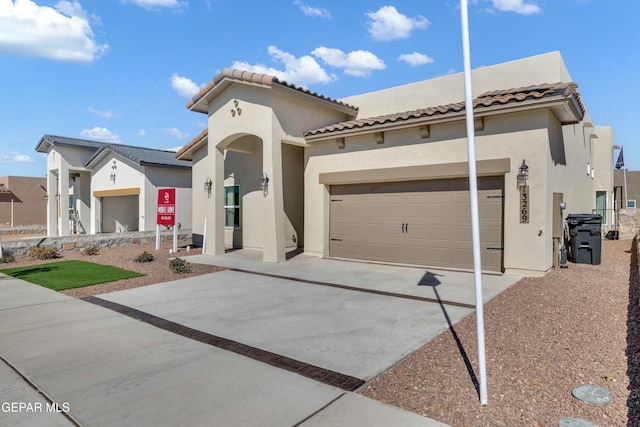 mediterranean / spanish house with concrete driveway, a tiled roof, an attached garage, and stucco siding