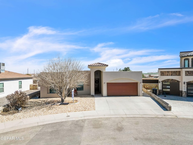 view of front facade with driveway, an attached garage, a tiled roof, and stucco siding