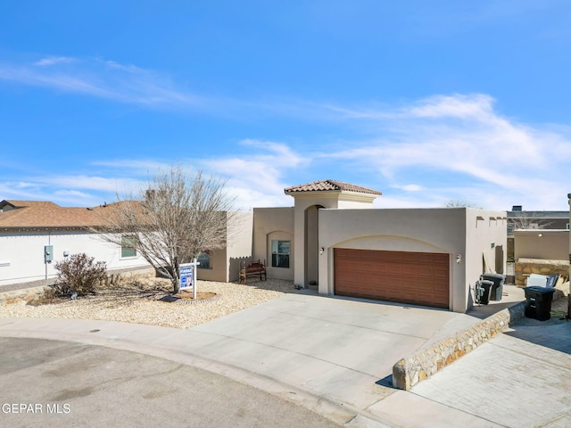 view of front of home with concrete driveway, an attached garage, a tile roof, and stucco siding