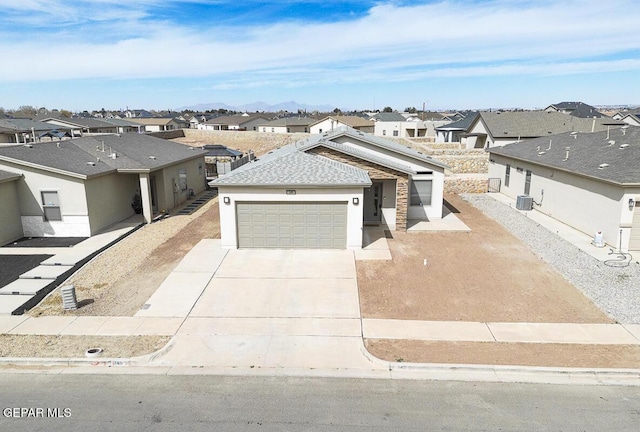 view of front of home featuring central AC unit, a garage, concrete driveway, a residential view, and stucco siding