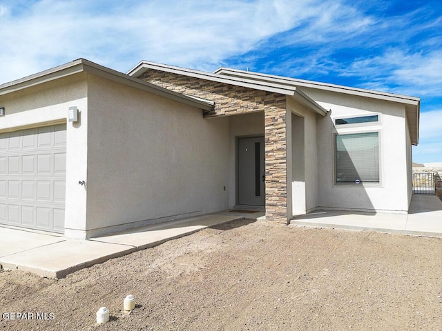 exterior space with a garage, stone siding, and stucco siding