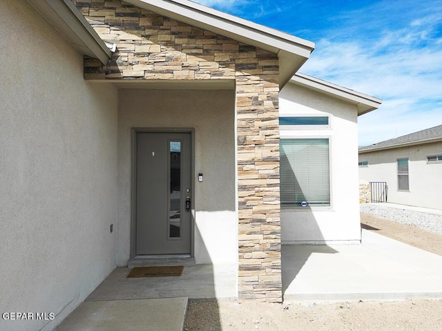 view of exterior entry with stone siding and stucco siding