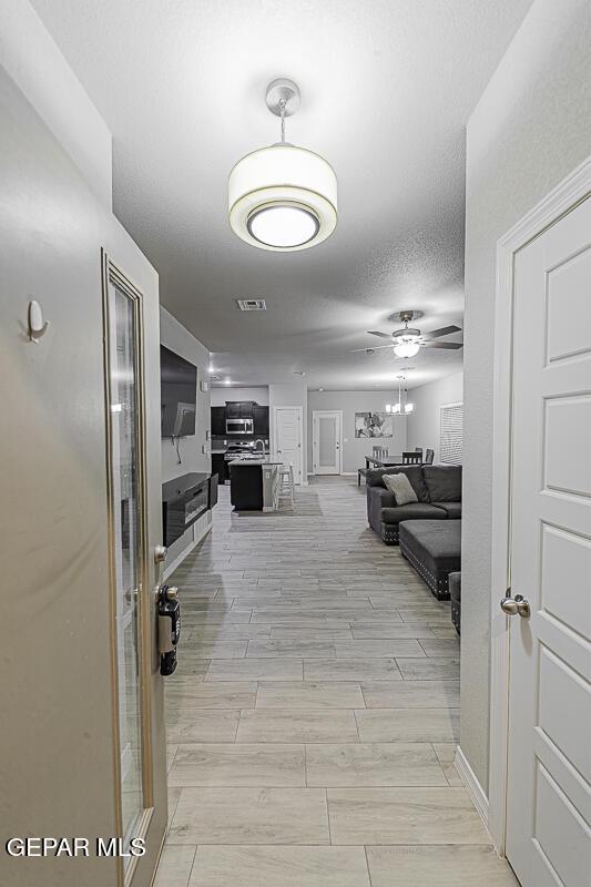 hall with wood tiled floor, visible vents, and a textured ceiling