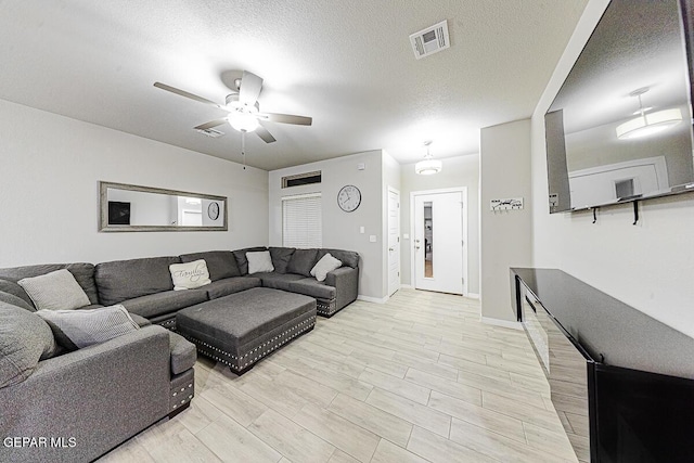 living area featuring baseboards, visible vents, a ceiling fan, a textured ceiling, and light wood-type flooring