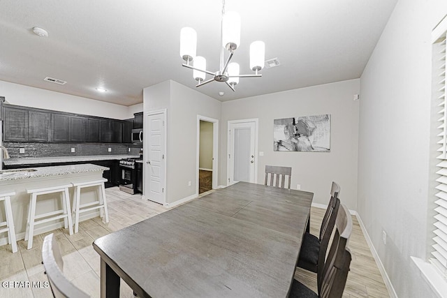 dining space featuring a chandelier, visible vents, light wood-style floors, and baseboards