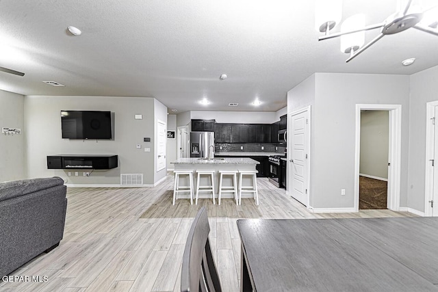 dining room with visible vents, light wood-style flooring, baseboards, and a textured ceiling