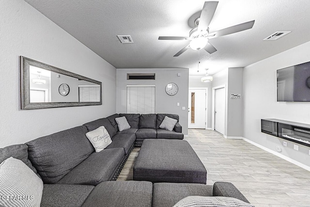 living room with light wood-style floors, visible vents, and a textured ceiling