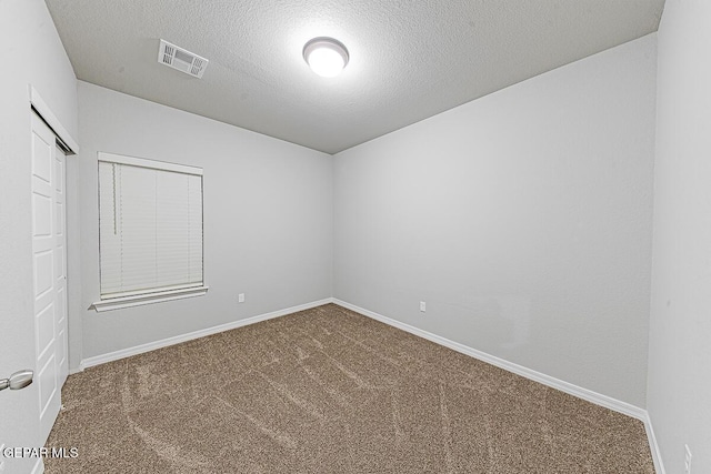 spare room with carpet floors, visible vents, and baseboards