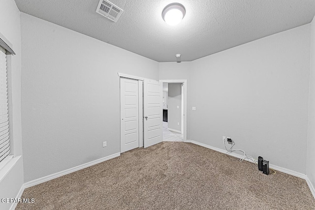 unfurnished bedroom with carpet floors, a closet, visible vents, a textured ceiling, and baseboards