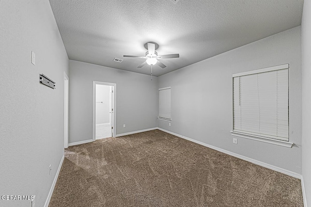 unfurnished room with visible vents, dark carpet, ceiling fan, a textured ceiling, and baseboards