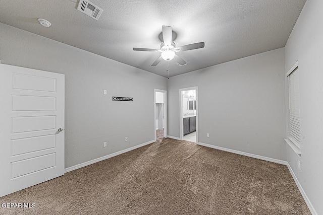 carpeted spare room featuring a textured ceiling, baseboards, visible vents, and a ceiling fan