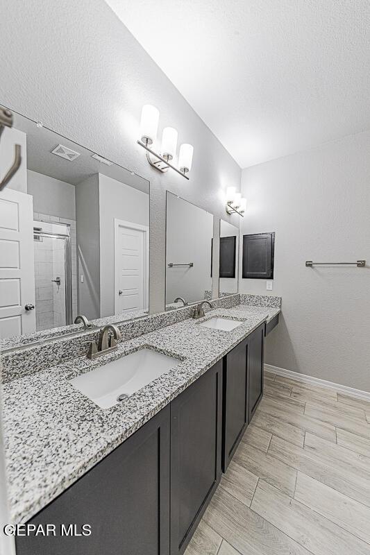 bathroom featuring double vanity, visible vents, a sink, and wood finish floors