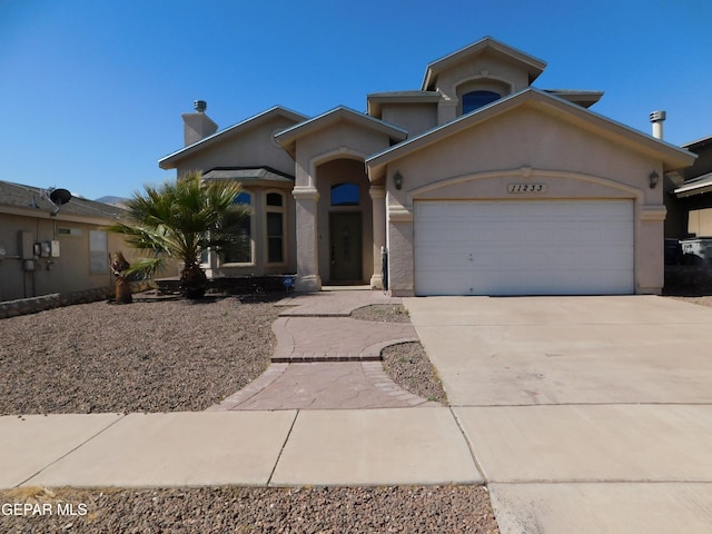 mediterranean / spanish home with an attached garage, a chimney, concrete driveway, and stucco siding