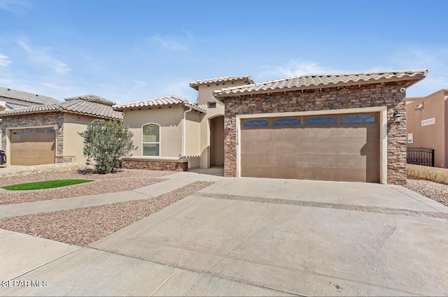 mediterranean / spanish-style house with an attached garage, a tile roof, stone siding, concrete driveway, and stucco siding