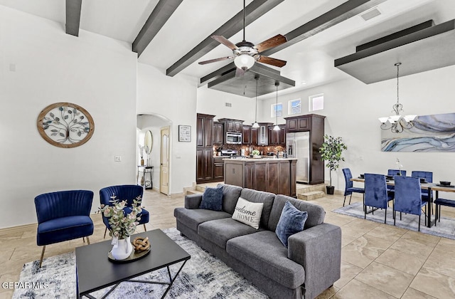 living area featuring arched walkways, beamed ceiling, ceiling fan with notable chandelier, and a towering ceiling