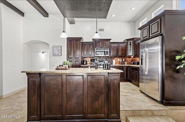 kitchen featuring a towering ceiling, visible vents, dark brown cabinets, appliances with stainless steel finishes, and tasteful backsplash