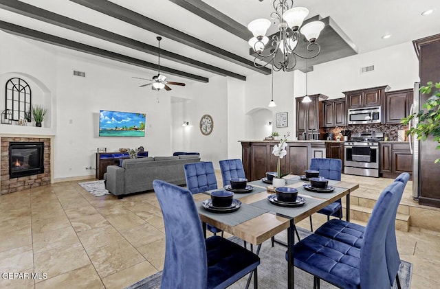 dining room featuring visible vents, arched walkways, a glass covered fireplace, a towering ceiling, and beamed ceiling