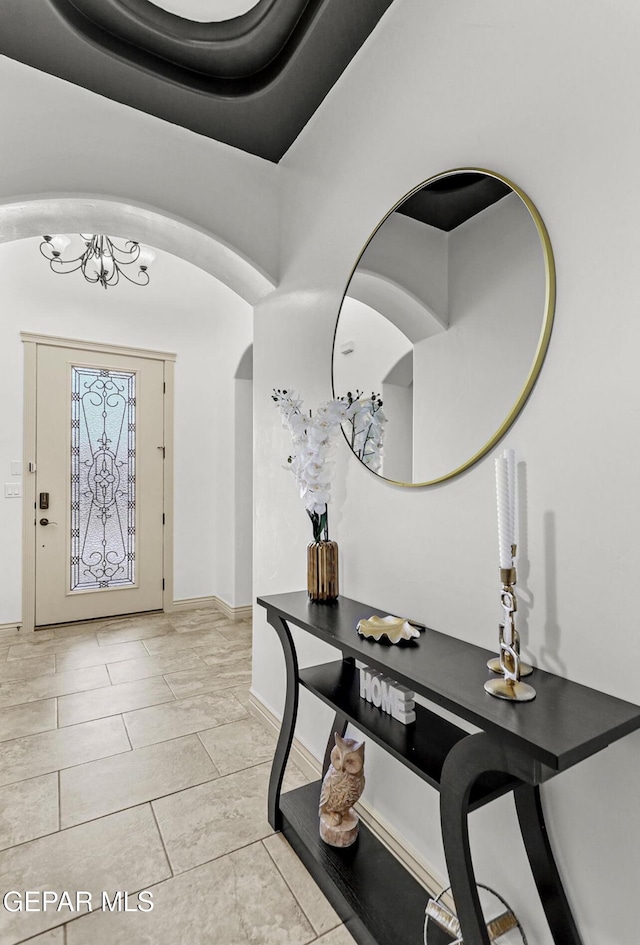 foyer entrance featuring arched walkways and baseboards