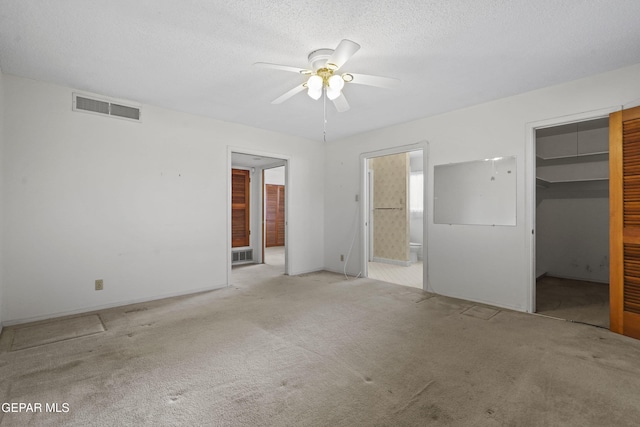 unfurnished bedroom featuring light colored carpet, visible vents, connected bathroom, and a textured ceiling