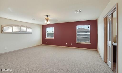 empty room with visible vents, light carpet, and baseboards