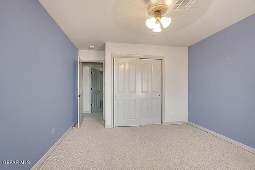 unfurnished bedroom with a closet, visible vents, light carpet, ceiling fan, and baseboards