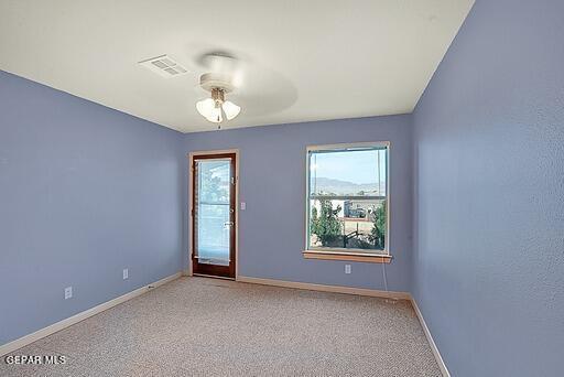 spare room featuring light colored carpet, visible vents, ceiling fan, and baseboards